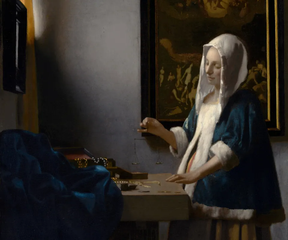 Detail of Woman Holding a Balance by Johannes Vermeer. A woman holds a small balance above a table with jewelry in a softly lit room.
