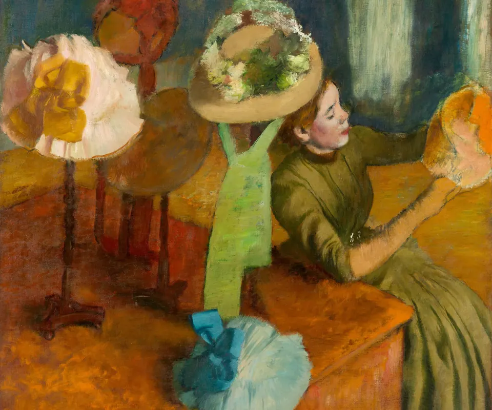 Detail of The Millinery Shop by Hilaire Germain Edgar Degas. A woman sits among decorated hats in a millinery shop.